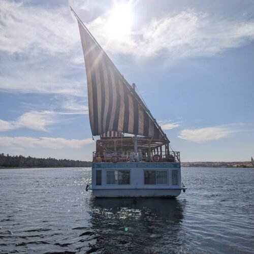 A dahabeya under sail on the Nile, the sun behind her rig