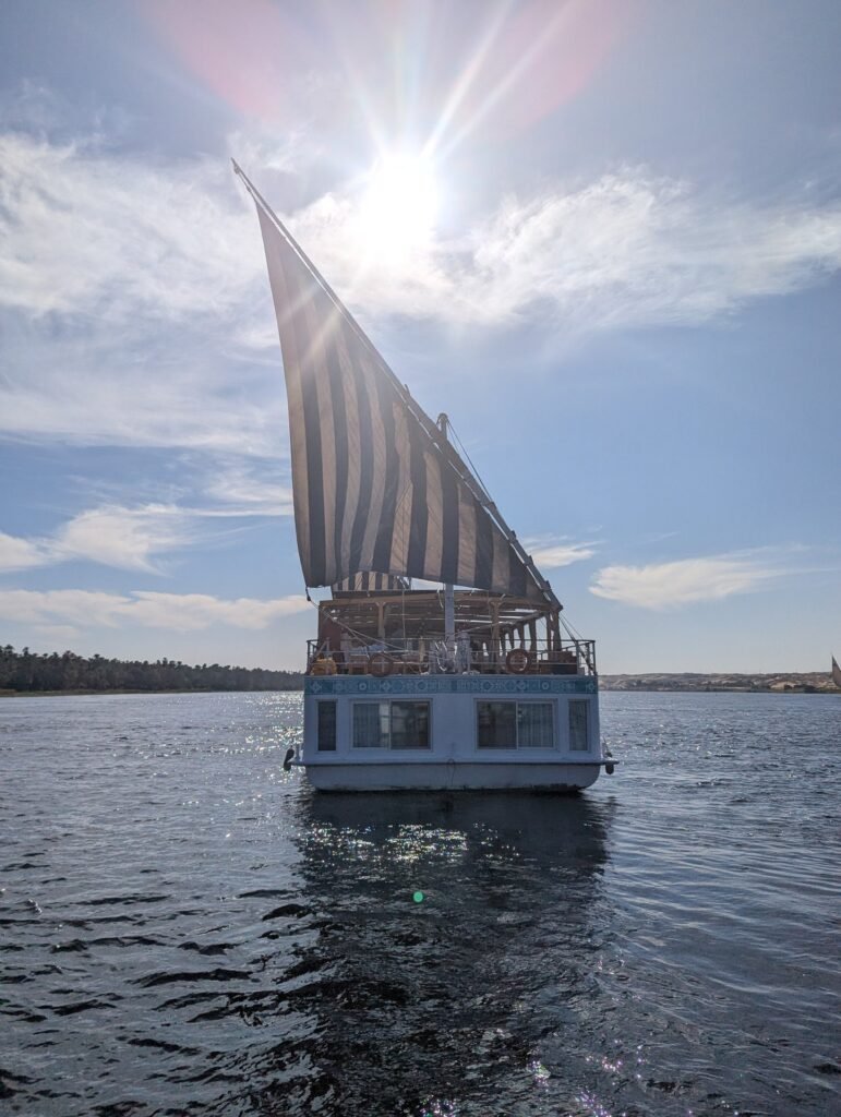 A dahabeya under sail on the Nile, the sun behind her rig