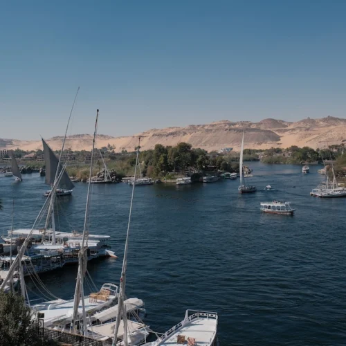 Feluccas and cruise boats moored along the Nile at Aswan, the desert escarpment on the far bank