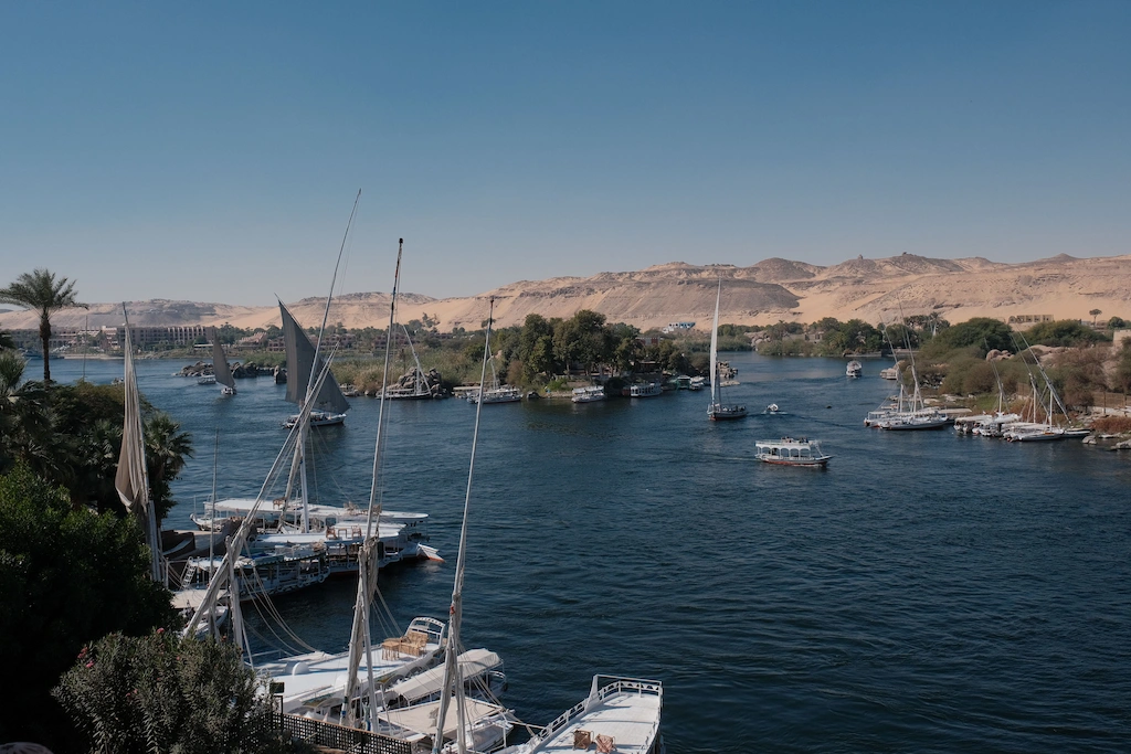 Feluccas and cruise boats moored along the Nile at Aswan, the desert escarpment on the far bank