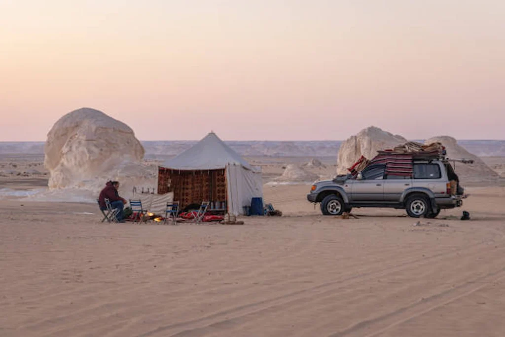 A desert camp with a four-wheel-drive among white chalk formations in the Western Desert