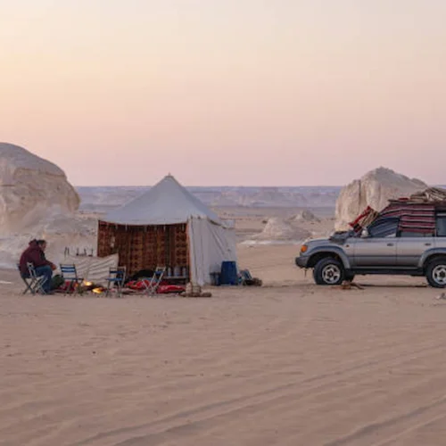 A desert camp with a four-wheel-drive among white chalk formations in the Western Desert