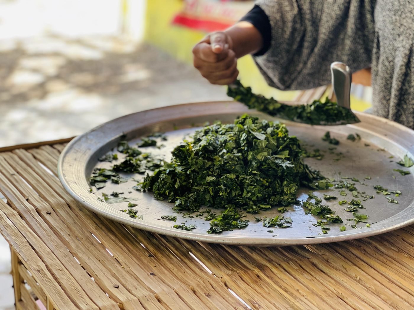 Finely chopped molokhia leaves on a round metal tray - ready for the stock