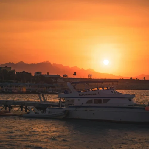 Sunset over the harbour at Hurghada, boats moored against an orange sky and the Red Sea mountains