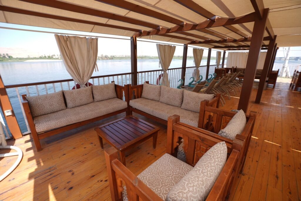 Cushioned sofas and a low wooden table in the shaded lounge on a dahabeya's upper deck