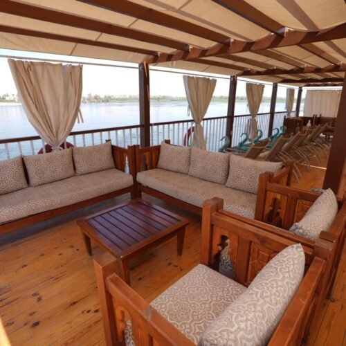 Cushioned sofas and a low wooden table in the shaded lounge on a dahabeya's upper deck